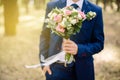 Pink and white roses in a stylish wedding bouquet which the groom holds in his hand. The groom in a dark blue stylish Royalty Free Stock Photo