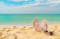 Pink and white sandals, sunglasses on sand beach at seaside. Casual fashion style flipflop and glasses. Summer vacation Royalty Free Stock Photo