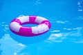 Pink-white swimming pool ring, float in refreshing blue water. Sunny day at resort. Royalty Free Stock Photo