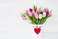 Pink and white tulips bouquet in white vase decorated with red heart. Valentines Day concept. Royalty Free Stock Photo