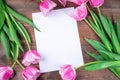 Pink white tulips and white sheet of paper on dark brown wooden background, horizontal, copy space, top view Royalty Free Stock Photo