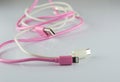 Pink and white USB cable on gray background