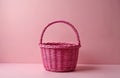 Pink wicker basket with twisted handle on pink background. Empty woven container on pastel surface. Isolated basket for picnic or Royalty Free Stock Photo