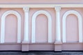 Pink windowless facade of the building with white columns and arches. Beautiful exterior. Background, wallpaper. Royalty Free Stock Photo