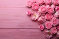 Pink wooden background adorned by a lovely frame of delicate pink roses