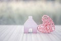 Pink wooden heart design with miniature pink wooden house over blurred background Royalty Free Stock Photo