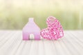 Pink wooden heart with miniature pink wooden house over blurred green garden background Royalty Free Stock Photo