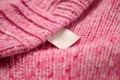 Pink wool sweater with an empty inner label on the neck. Blank laundry care clothes label on knitted fabric background, mockup, Royalty Free Stock Photo