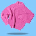 Pink wool sweater, levitates as if dancing, casts a shadow, on a blue background Royalty Free Stock Photo