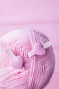 Pink woolen thread and two pink hearts clothespins on a pink wooden background. Top view, free space