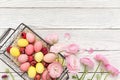 Pink and yellow easter eggs in basket with ranunculus flowers on white wooden background. Spring concept. Top view, copy space Royalty Free Stock Photo