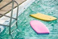 Pink and yellow floats resting on the surface of a tranquil, blue swimming pool on a sunny day Royalty Free Stock Photo