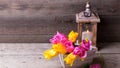 Pink and yellow spring tulips in box and candle in lantern on Royalty Free Stock Photo