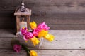 Pink and yellow spring tulips in box and candle in lantern on Royalty Free Stock Photo