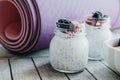 Pink yoga mat and Pudding with chia seeds, yogurt and fresh fruits: Strawberries, blueberries and blackberries in glass jars on w Royalty Free Stock Photo