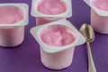 Pink yogurt cup with defocused cups on purple background