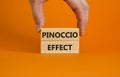 Pinoccio effect symbol. Concept words Pinoccio effect on wooden blocks on a beautiful orange background. Businessman hand. Royalty Free Stock Photo