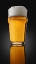 A pint of beer with foam in glass with water drops on a dark background with gradient lighting and reflection in the surface Royalty Free Stock Photo