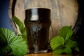 Pint dark beer nicely with a leaf of hops on the background of the barrel. Close up Royalty Free Stock Photo