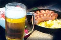 Pint of frothy beer in a misted glass, on the background of a delicious dinner