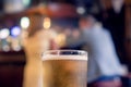 Pint glass of cold lager beer of cider in focus. Well dressed woman and man out of focus in the background. Date of flirt concept Royalty Free Stock Photo