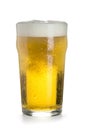 Pint of light cold beer in a glass with a thick cap of foam, bubbles and drops of condensate, isolated on a white Royalty Free Stock Photo