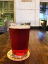 A pint of red beer on a wooden table in a bar. Transparent beer glass of classic shape