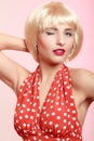 Pinup girl in blond wig and retro red dress winking. Vintage. Royalty Free Stock Photo