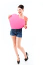 Pinup girl holding pink heart and happy smiling, full length. Retro portrait of young cheerful woman in pin-up style Royalty Free Stock Photo