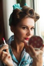 Pinup look dressed woman paints her lips with red lipstick