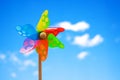 Pinwheel on blue sky with clouds. Colorful wheel kids toy