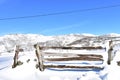 Winter landscape with snowy field and mountains and wooden gate. Blue sky, sunny day. Piornedo, Lugo, Galicia, Spain. Royalty Free Stock Photo