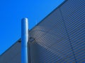 Pipe chimney made of stainless steel attached on the wall of an industrial metal hall. Royalty Free Stock Photo