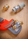Pipe fixtures and monkey wrench on wooden board close up Royalty Free Stock Photo