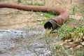 Dirty water pours onto the ground from a water pipe. Royalty Free Stock Photo