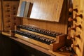 Pipe organ console with two keyboards also called manuals and wooden stop knobs for registration in the St. Mary`s Church of Gudo