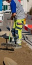 Pipeline mechanic scrubbing sand in construction site in front of a construction vehicle and trailer with shovel in foreground Royalty Free Stock Photo