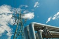 pipeline and power line support, in the photo pipeline and power line tower close-up against the background of blue sky and clouds