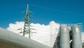 pipeline and power line support, in the photo pipeline and power line tower close-up against the background of blue sky and clouds