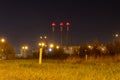 Pipes of an industrial factory at night. Red signal lights are lit at the top of the pipes.