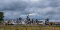 Pipes of woodworking enterprise plant sawmill against a gloomy gray sky. Air pollution concept. Panorama of industrial landscape