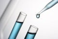 Pipette adding blue fluid in test tube close up. Royalty Free Stock Photo