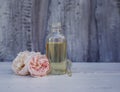 Pipette and the bottle of rose oil lies on the wooden table in the garden next to the delicate pink fragrant flowers Royalty Free Stock Photo