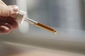 Pipette with serum or cosmetic liquid close-up in hand in soft focus on brown background. Soothing cbd oil. Alternative Royalty Free Stock Photo