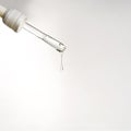 Pipette with drop of serum or hyaluronic acid on gray background.