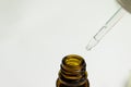 Pipette dropping liquid into an amber glass bottle on blurred background - concepts of skincare Royalty Free Stock Photo