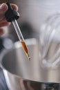 Pipette with vanilla extract close-up in hand with soft focus against the backdrop of a blurred kitchen. Royalty Free Stock Photo