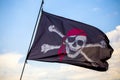 Pirate flag waving on the wind with a blue sky background Royalty Free Stock Photo