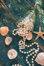 The pirate`s treasure - white pearls and shells on blue wooden background, vintage fashion