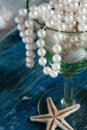 The pirate`s treasure - white pearls and shells on blue wooden background, vintage fashion